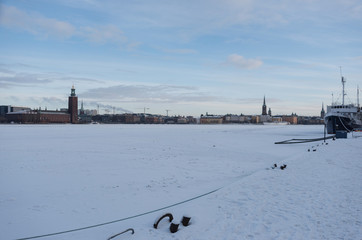 Boats and City hall in Stockholm at Kungsholmen	a winter day in pale sun light