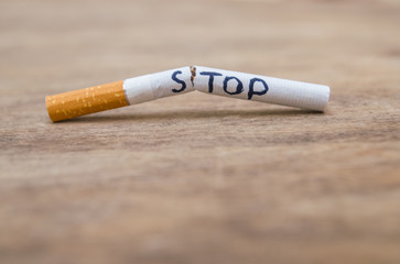 broken cigarette with the word stop on a wooden background; stop smoking close up concept