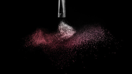 Cosmetic brush with red cosmetic powder spreading for makeup artist and graphic design in black background