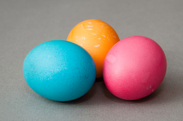 Fototapeta na wymiar Three easter eggs blue pink orange color on a gray background. View from the side.