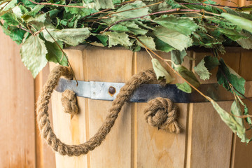 Birch broom on a wooden bucket in the bath