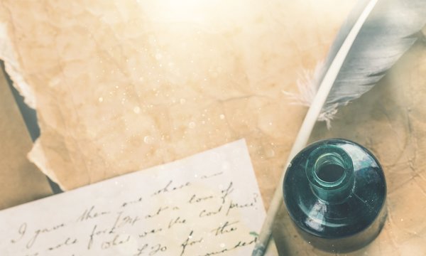 White feather quill pen, glass inkwell and old letter