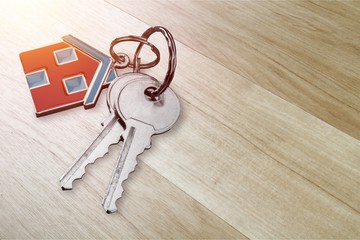 House keys with trinket on wooden background
