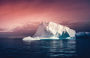 The huge iceberg on the colorful sunset sky background. Breathtaking magic Antarctic landscape. The...