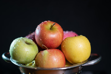 Yellow, green and red apples against the black background
