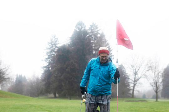 Man standing on a golf course holding a golf flag, Germany