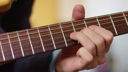 Close up hand of guitarist slides on fretboard