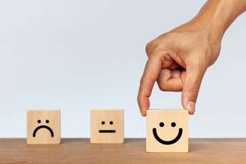 Hand of client show a feedback with smiley face wood cube. Service rating, satisfaction concept