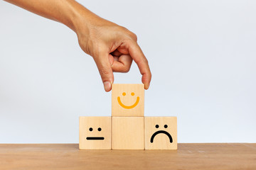 Hand of client show a feedback with smiley face wood cube. Service rating, satisfaction concept
