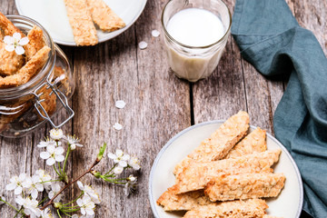 Homemade oatmeal cookies in a bowl and glass jar and cup of milk on grey vintage wooden table.  Traditional Swedish cookies Havrekakor