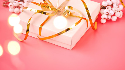 St. Valentine day background. Gift box with gold ribbon and lights on a pink background. Holiday background.
