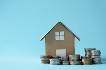 House model around with stacking coins money on blue background. Saving and investment to real estate concept. -image.