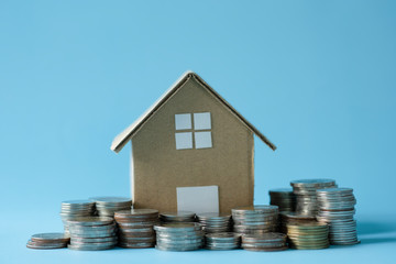 House model around with stacking coins money on blue background. Saving and investment to real estate concept. -image.