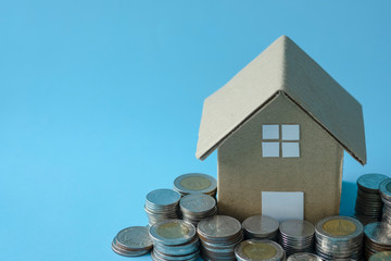 House model around with stacking coins money on blue background. Saving and investment to real estate concept. -image.