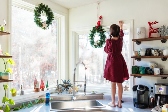 Girl standing on a kitchen worktop putting up  Christmas decorations