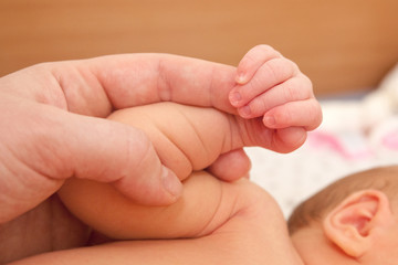 The baby clings to his mother's finger