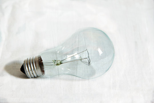 Electric incandescent lighting glass bulb with tungsten spiral isolated by white background.