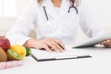 Female nutritionist counting calories in hospital, closeup