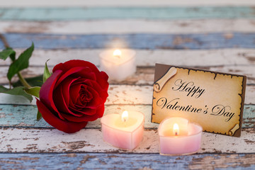 Obraz na płótnie Canvas Greeting card with Happy Valentine's Day text, single red rose, and candle lights darker