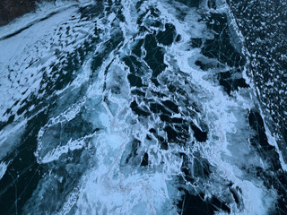 Obraz premium View of the frozen Lake Baikal in winter from drone. Ice cracks on lake. Abraham Lake, Lake Superior. Cracked ground of frozen lake Baikal, Irkutsk, Siberia, Russia. Slippy and cold frozen ground.