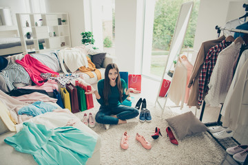 Attractive pretty nice funny cheerful cheery girl sitting on floor among different clothes making...