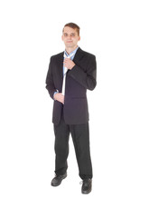 Young man standing in a suit fixing his tie