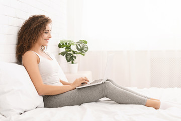 Woman lying in bed and watching something on laptop