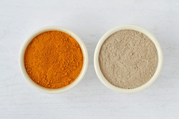 Homemade face mask made out of turmeric and moroccan rhassoul (ghassoul) clay on wooden background