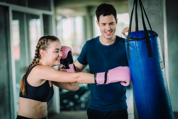 Fototapeta na wymiar Fit beautiful woman boxer hitting a huge punching bag exercise class in a gym. Boxer woman making direct hit dynamic movement. Healthy, sport, lifestyle, Fitness, workout concept. With copy space.