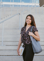 Fototapeta premium Content young Asian university student standing by campus stairs