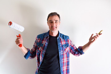 Smiling man with painting tools and white wall behind