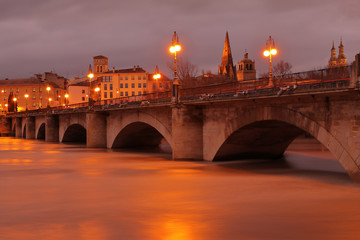 Obraz premium BRIDGE OF STONE WITH LIGHTS IN THE NIGHT THAT CROSSES THE RIVER EBRO WITH A CITY AND A FEW CATHEDRALS TO THE BOTTOM