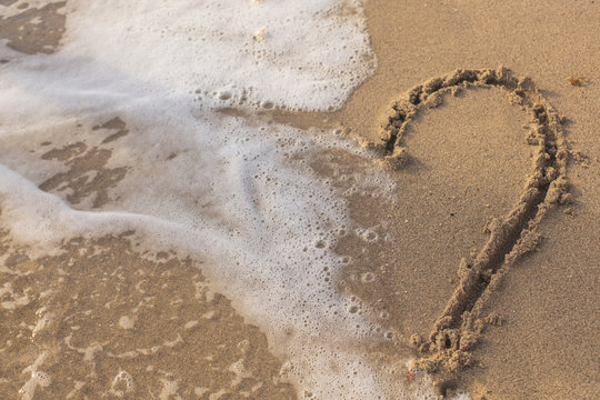  Heart on the Sand in the Beach Being Washed Away by a Wave.