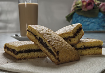 biscotti farciti al cioccolato fondente e bicchiere caffè e latte