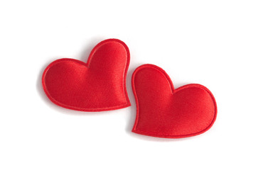 Two red fabric hearts sit close together on a clean white background. Concept of: Romantic closeness
