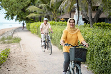 Obraz premium happy senior muslim couple exercising riding bicycle together 