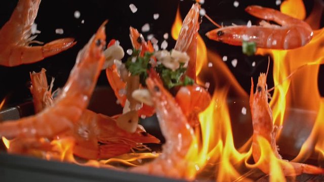 Super slowmotion footage of throwing fresh prawns and seasoning on ignited pan, 1000fps 4k