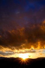 Naklejka premium Sunset on Mountains Horizon Clouds Sunstar Sun star Glowing