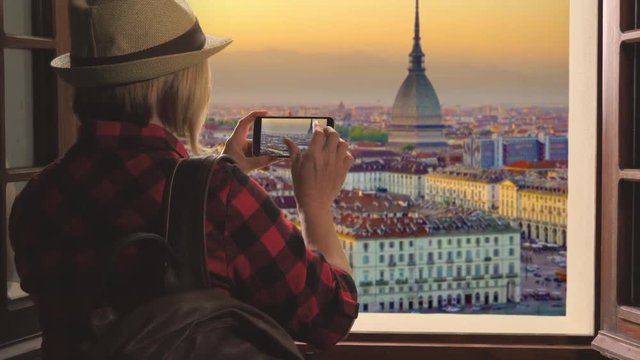 tourist taking picture of turin skyline at sunset,woman takes photo of mole antonelliana using smartphone