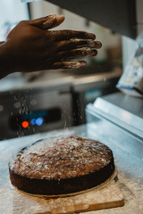 Hands of black cook clapping with floor while cooking a chocolate cake for a restaurant, kitchen and oven in the background