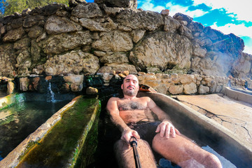Man enjoying and relaxing in natural thermal water roman spa.