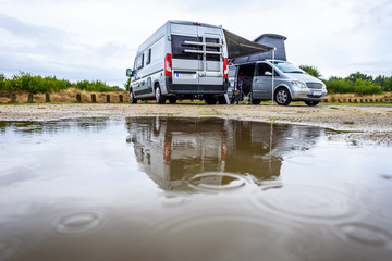 Campervan or motorhome camping on rainy day with rain puddles.