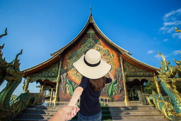 Fototapeta premium Woman in black shirt holding hands men at temple in Thailand.