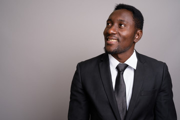 Young handsome African businessman against gray background