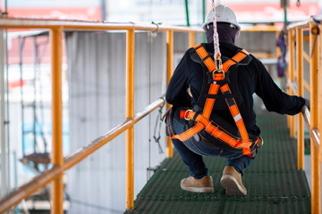 Construction worker wearing safety harness and safety line working on construction. - 245974599