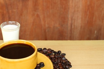 Coffee cup and coffee beans on wooden background.