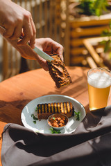 Male hands spreading pate on a bread toast with cold beer, man having lunch in a restaurant,...