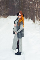 Fototapeta na wymiar Winter portrait of pregnant woman in forest