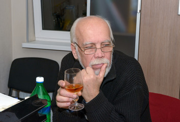 Portrait of senior man with glass of drink in his hand.