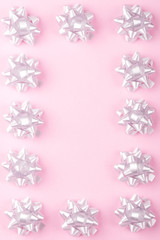 Minimal background composition of plastic  decorative gift bows,in the form of a frame, on a pink background. Holiday concept.Copy space.